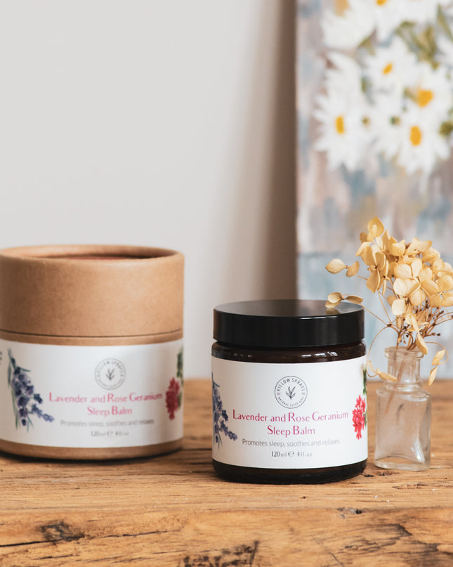 A lavender and rose geranium sleep balm on a bedside table