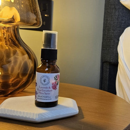 Small bottle of lavender essential oil pillow spray on a white coaster with a blurred background