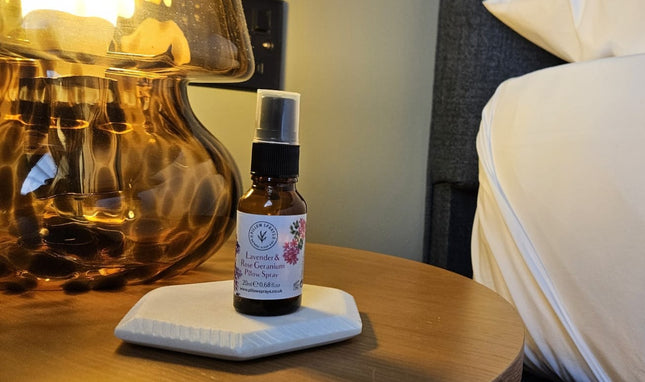 Small bottle of lavender essential oil pillow spray on a white coaster with a blurred background