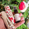 Hand holding a small bottle of essential oil pillow spray with decorative paper against a Christmas tree background
