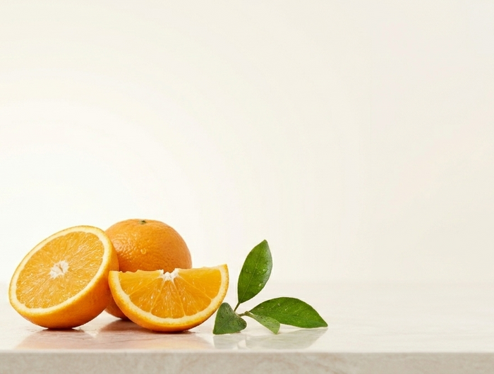 Bottle of natural spray with oranges and leaves on a light background