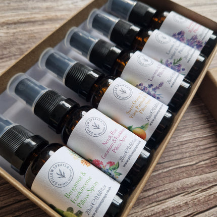 Row of small pillow spray bottles with labels in a cardboard box on a wooden surface