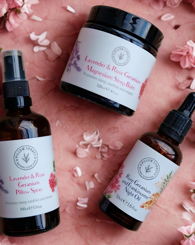 Three wellness products from Pillowsprays - a Magnesium Sleep Balm, a Night Oil and a Pillow Spray on a pink floral background