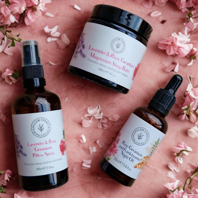 Three wellness products from Pillowsprays - a Magnesium Sleep Balm, a Night Oil and a Pillow Spray on a pink floral background