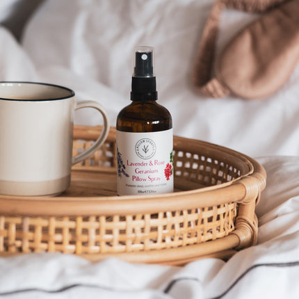 A Pillow Spray on a wicker tray on a bed