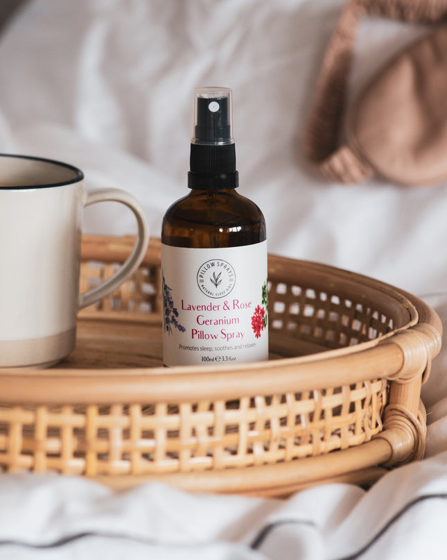 A Pillow Spray on a wicker tray on a bed