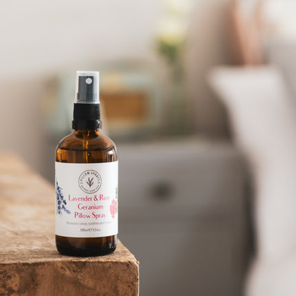 A Lavender and Rose Geranium Pillow Spray in an amber glass bottle on a shelf