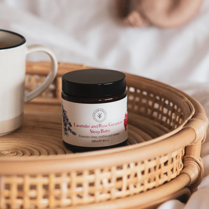 A lavender and rose geranium sleep balm on a wicker tray